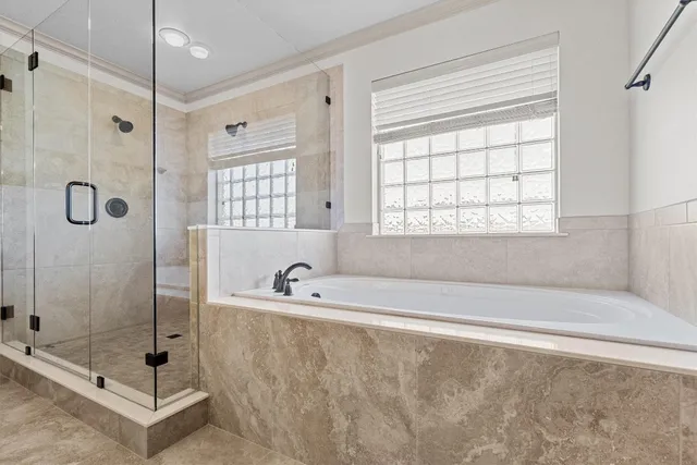 a bathroom with a tub a window and a glass door shower
