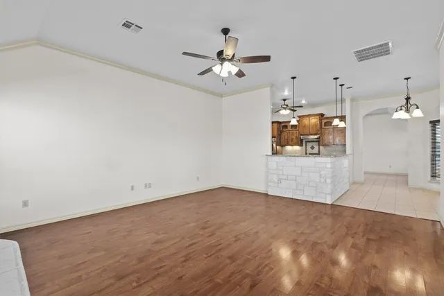 an empty room with wooden floor ceiling fan and window