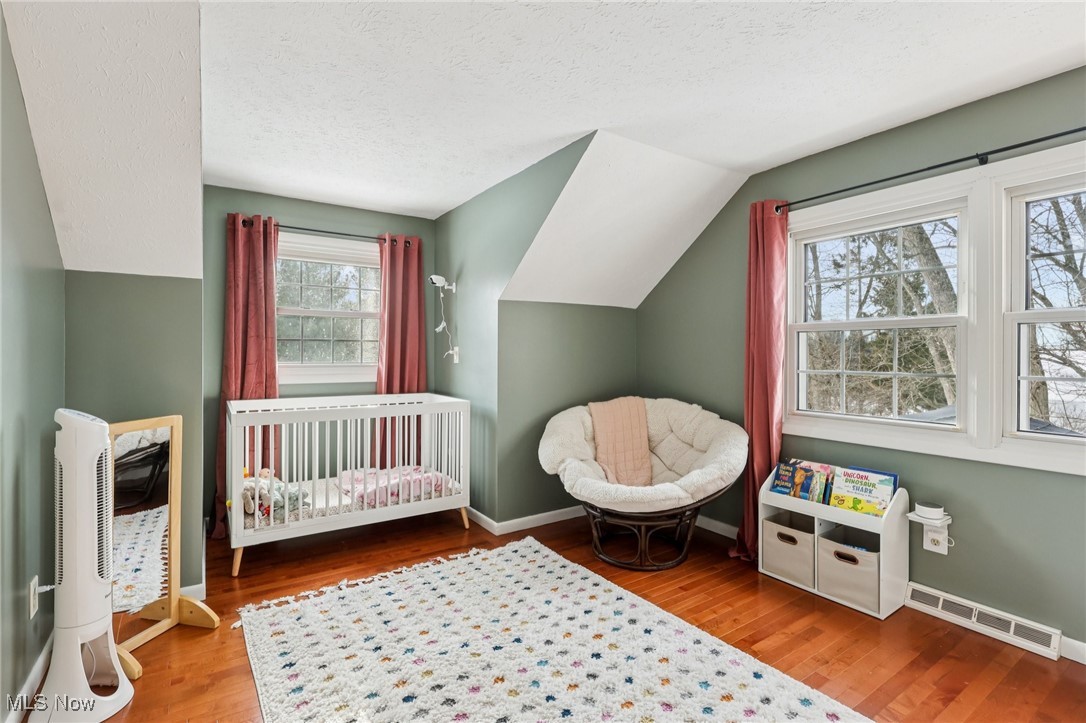 445 Center Road Hinckley, OH 44233 - Photo 25 of 50 Bedroom with vaulted ceiling, a crib, light wood-style flooring, and a textured ceiling
