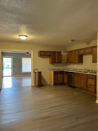 an empty room with wooden floor chandelier fan and windows