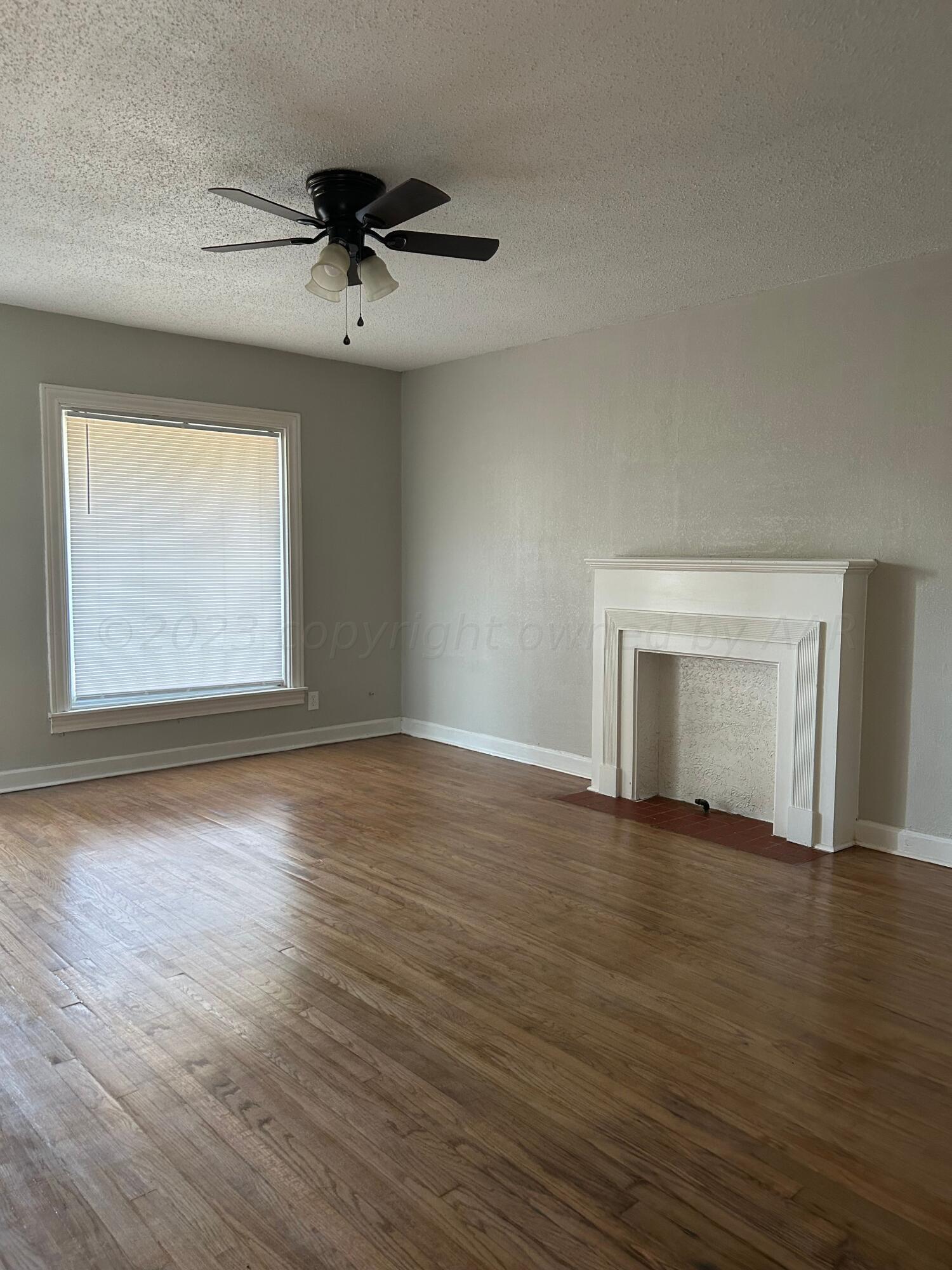 1408 Southwest 12th Avenue Amarillo, TX 79102 - Photo 7 of 25 an empty room with wooden floor chandelier fan and windows