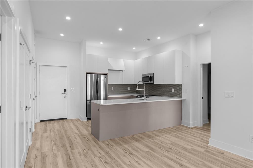 1155 Custer Avenue Southeast, Unit 301 Atlanta, GA 30316 - Photo 6 of 22 a large kitchen with stainless steel appliances a large counter top and wooden floors