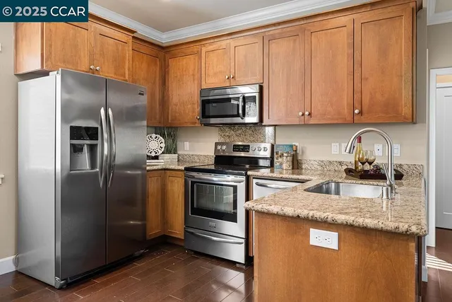 a kitchen with granite countertop stainless steel appliances a stove a refrigerator a sink a counter space and cabinets