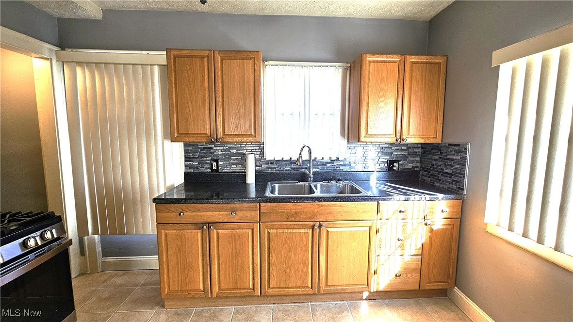 887 Rondel Road Cleveland, OH 44110 - Photo 17 of 34 Kitchen with sink, decorative backsplash, stainless steel range with gas stovetop, and light tile patterned floors