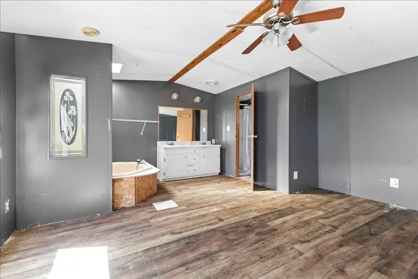 a view of a hallway with wooden floor and a bathroom