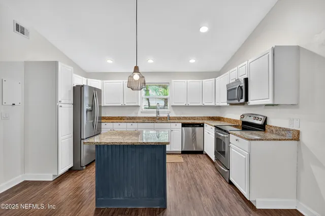 a bedroom with a bed a dresser and a chandelier
