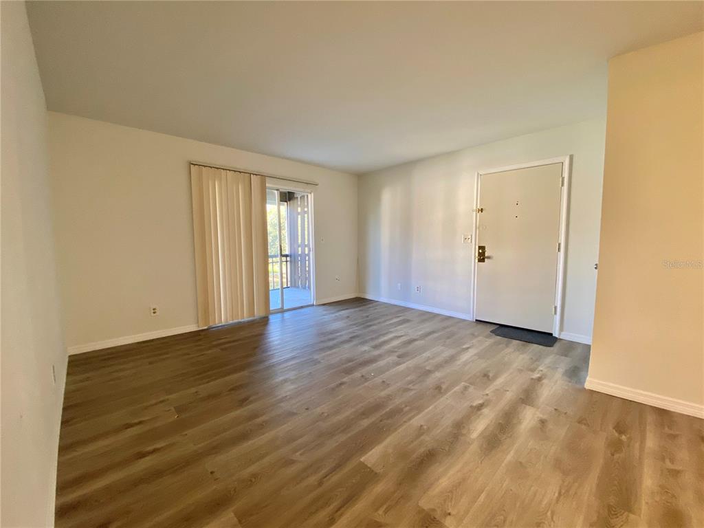6519 West Newberry Road, Unit 1211 Gainesville, FL 32605 - Photo 4 of 10 an empty room with wooden floor and windows