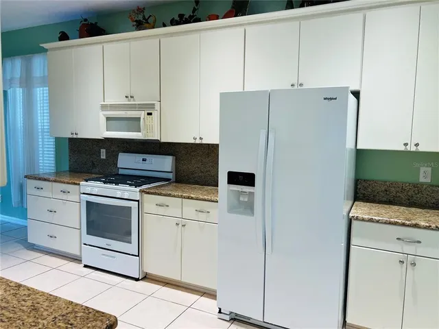 a kitchen with white cabinets and white appliances