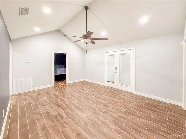 a view of a room with a ceiling fan and wooden floor