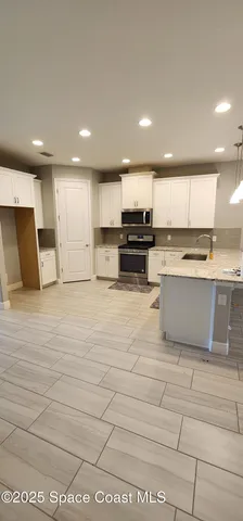 a large kitchen with kitchen island a sink a stove a refrigerator and a cabinets
