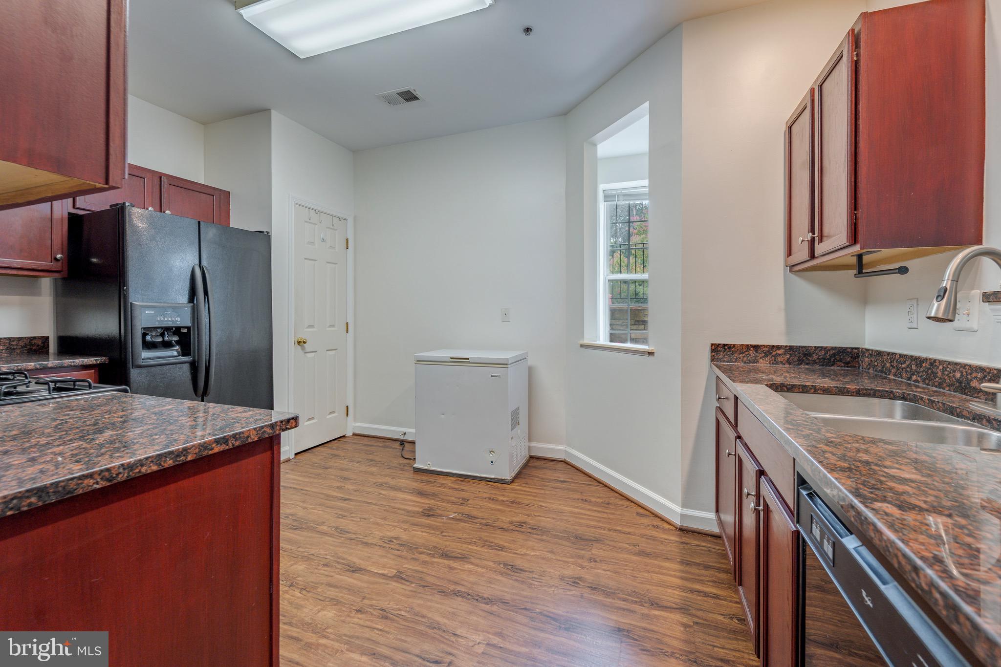 8611 Willow Leaf Lane Odenton, MD 21113 - Photo 11 of 33 a kitchen that has a sink a stove and a wooden floor