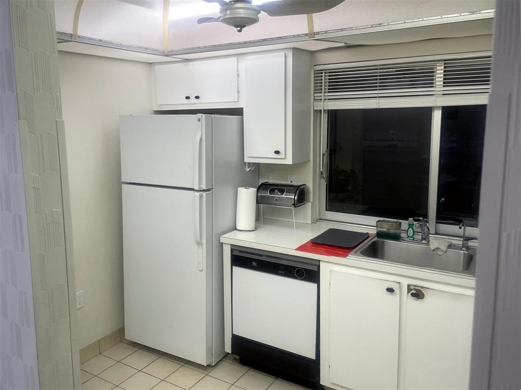 9301 Lime Bay Boulevard, Unit 204 Tamarac, FL 33321 - Photo 25 of 30 a kitchen with a sink and white cabinets