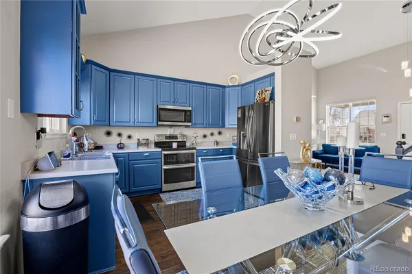 a kitchen with granite countertop stainless steel appliances a table chairs and a refrigerator