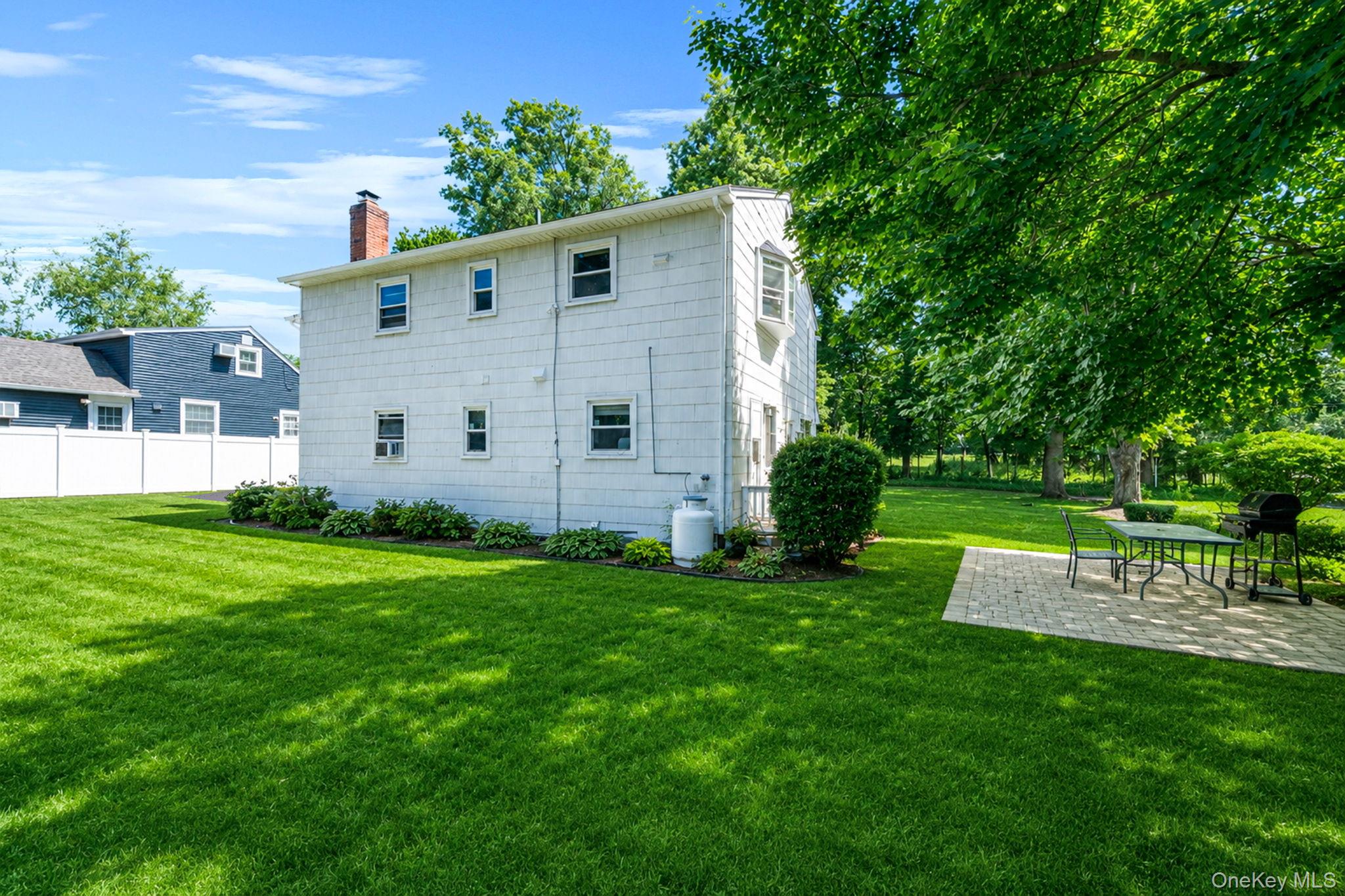 31 Crooked Hill Road Huntington, NY 11743 - Photo 29 of 32 Expansive backyard featuring a lush lawn, mature trees, and a paver patio