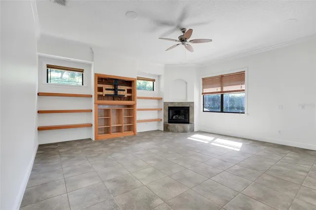 a view of a livingroom with a fireplace a ceiling fan and windows