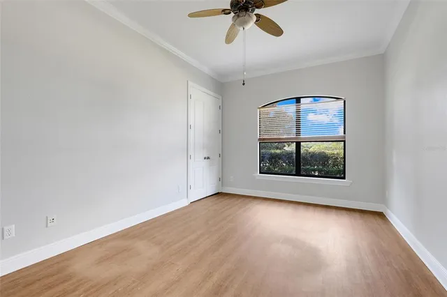 an empty room with wooden floor chandelier fan and windows