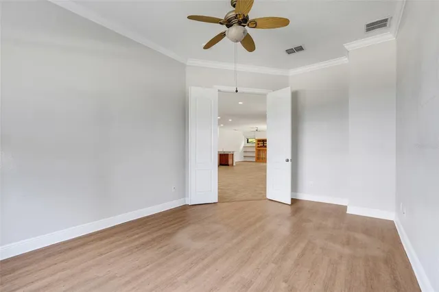 a view of empty room with wooden floor and ceiling fan