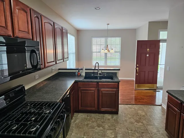 a kitchen with stainless steel appliances granite countertop a stove a sink and a microwave