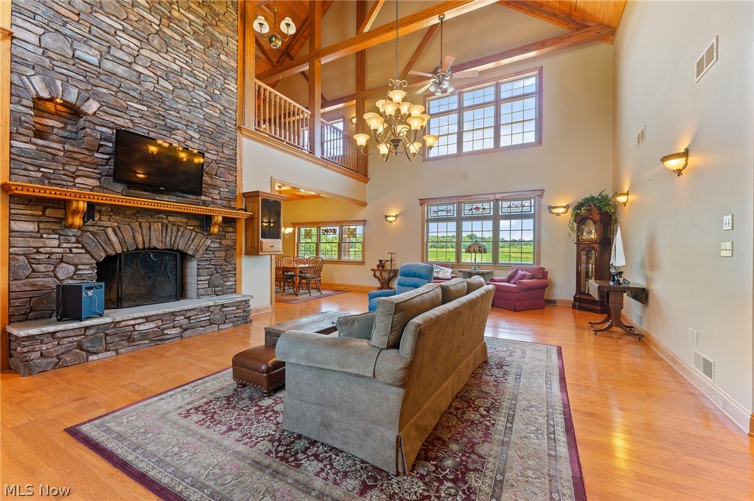 13721 Beaver Springfield Road New Springfield, OH 44443 - Photo 10 of 48 Living room with a fireplace, wood-type flooring, ceiling fan with notable chandelier, beam ceiling, and a towering ceiling