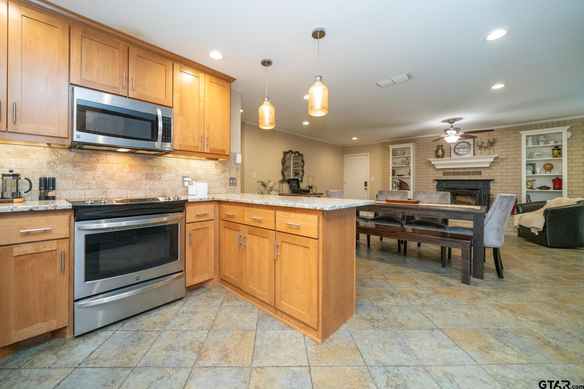 102 Randal Lane Pittsburg, TX 75686 - Photo 24 of 42 a kitchen with stainless steel appliances granite countertop a stove top oven a sink dishwasher a dining table and chairs with wooden floor
