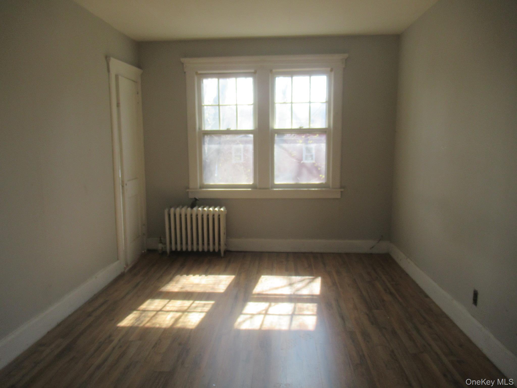 72 Waterstone Road Greenwood Lake, NY 10925 - Photo 14 of 20 Room featuring wood-finish flooring, a double window with white trim, and a wall-mounted radiator