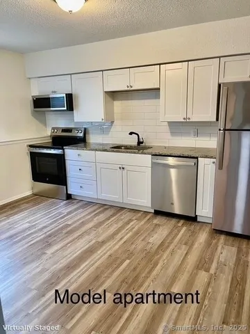 a kitchen with granite countertop a refrigerator and a stove top oven