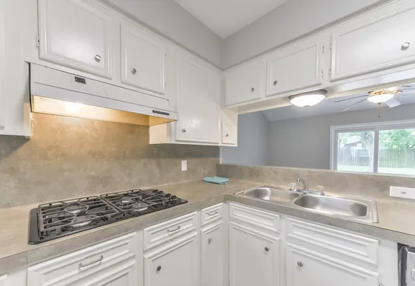 a kitchen with granite countertop white cabinets and white appliances