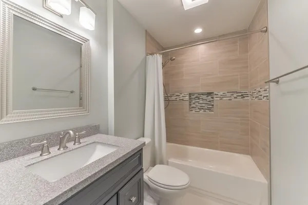 a bathroom with a granite countertop sink toilet and shower