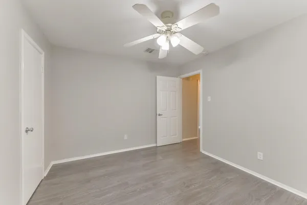 an empty room with wooden floor and chandelier fan