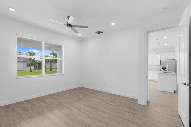 an empty room with wooden floor a ceiling fan and windows