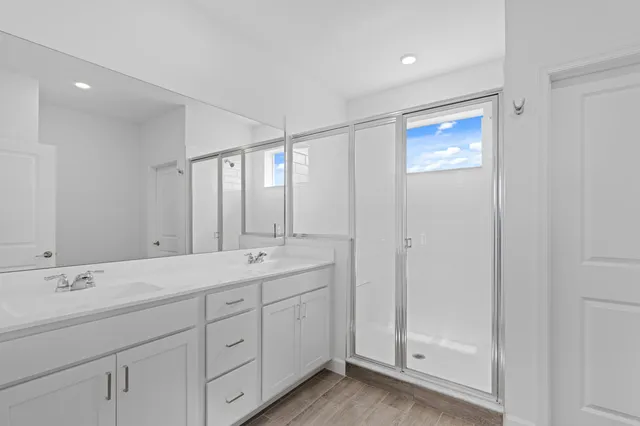 a spacious bathroom with a double vanity sink a large mirror and shower