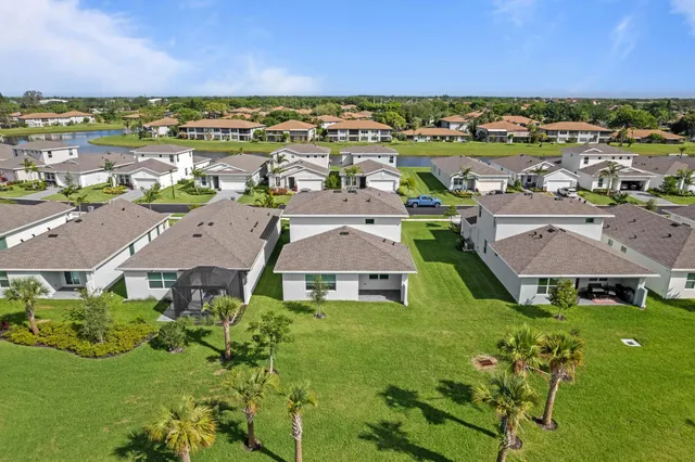 a view of a white house with a big yard and large trees