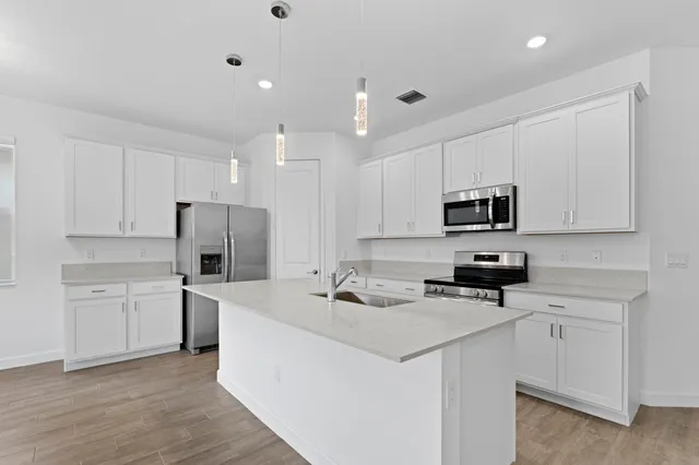 a kitchen that has a lot of white cabinets and stainless steel appliances