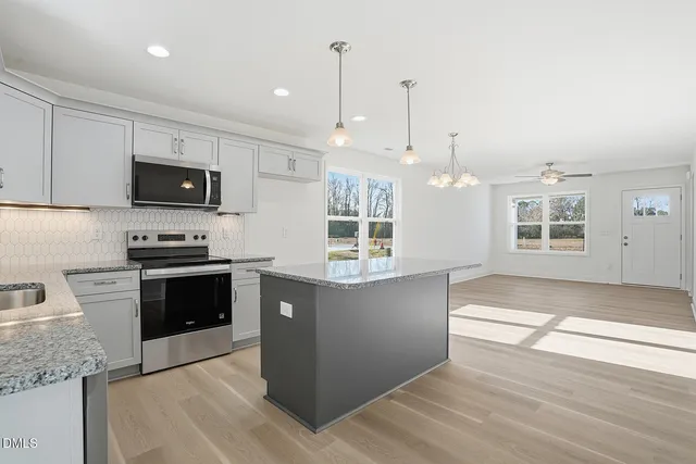 a kitchen with granite countertop a stove a sink and a wooden floors