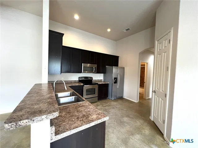 a kitchen with stainless steel appliances granite countertop a sink stove and refrigerator