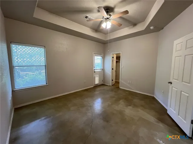 an empty room with windows and fan