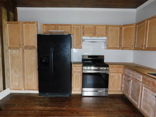 a kitchen with granite countertop a refrigerator stove and cabinets