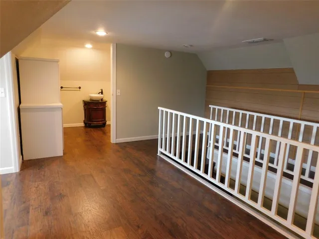 a view of a hallway with wooden floor and stairs