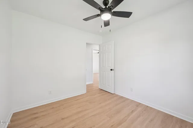 an empty room with a ceiling fan and wooden floor