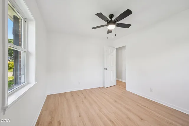 an empty room with a window and ceiling fan