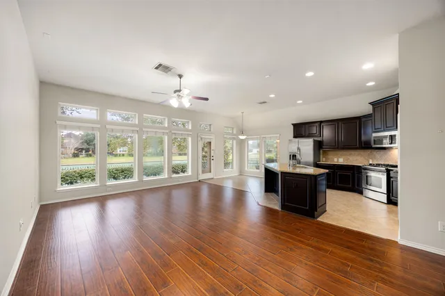 a open kitchen with stainless steel appliances granite countertop a stove top oven a sink and dishwasher with wooden floor