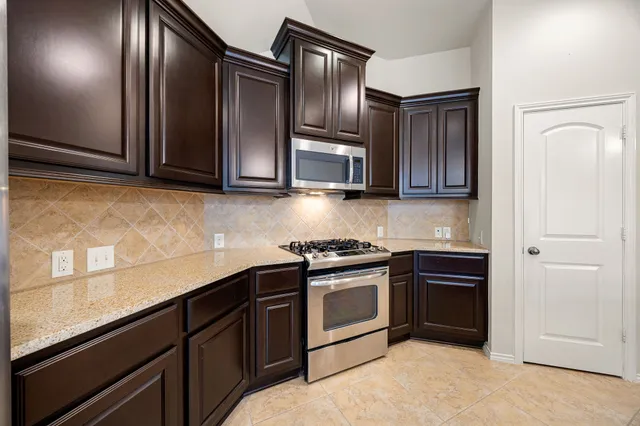a kitchen with granite countertop stainless steel appliances and wooden cabinets
