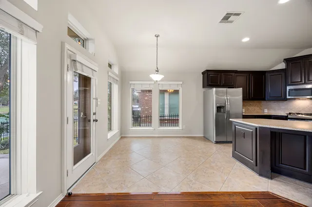 a open kitchen with stainless steel appliances granite countertop a refrigerator a oven a sink with island and chairs