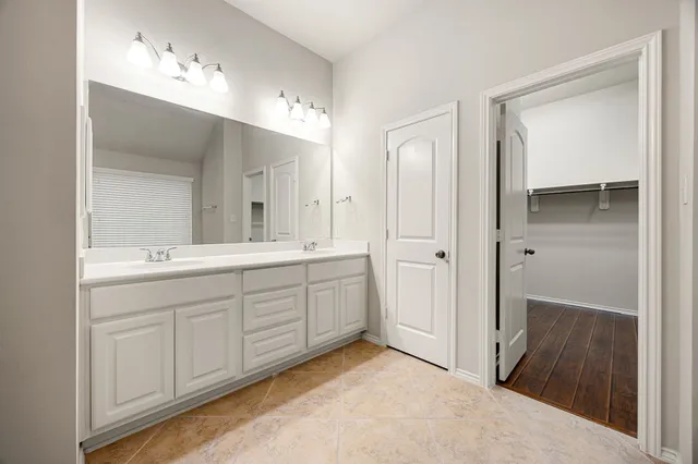 a spacious bathroom with a double vanity sink a mirror and a shower