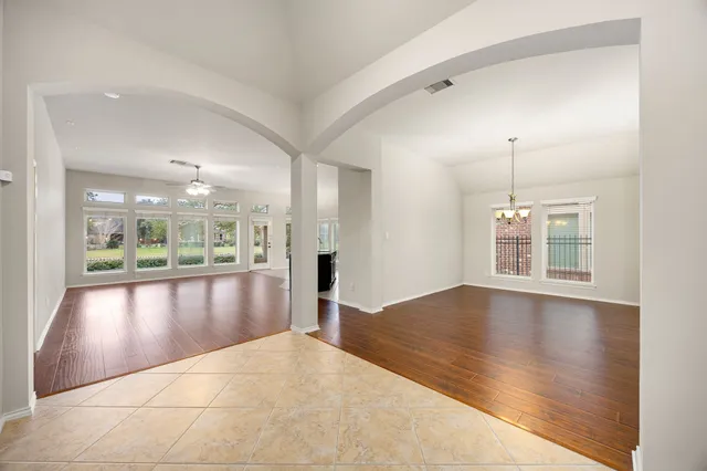 a view of an empty room with window and wooden floor