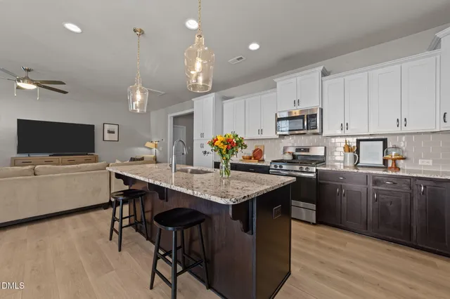 a kitchen with kitchen island a dining table chairs stainless steel appliances and cabinets