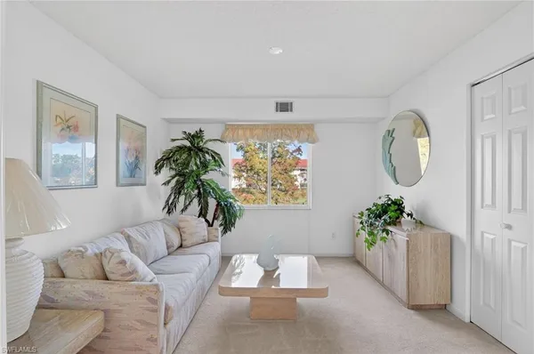 a living room with furniture flowers and a potted plant