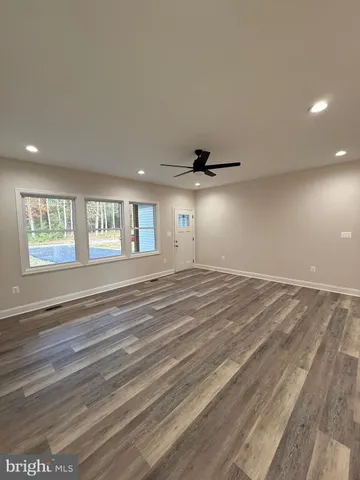 a view of an empty room with window and wooden floor