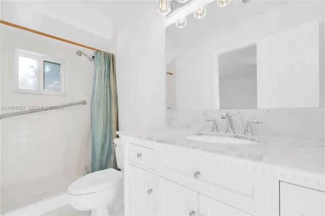 a bathroom with a granite countertop sink toilet and shower