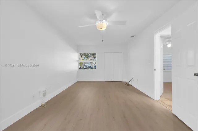 an empty room with a ceiling fan and a window